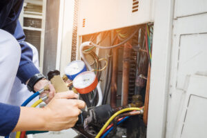 J&J Comfort AC technician using manifold gauge set to measure pressure of refrigerant.