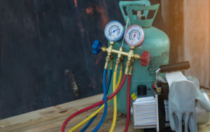 A tank of refrigerant next to a pair of gloves on a table.