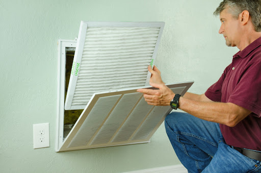 A man installing a new HVAC air filter.