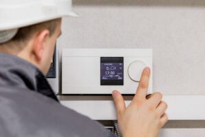 Johnson & Johnson HVAC technician programming thermostat for new air conditioner unit.