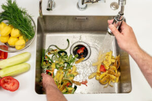 Sink filled with food scraps going down the garbage disposal